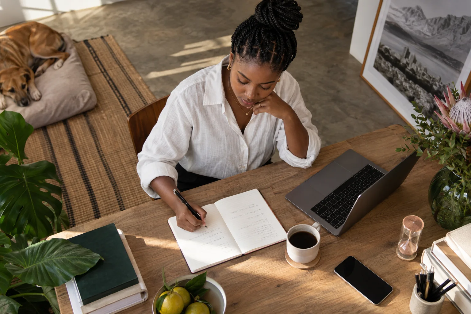 Overhead portrait of a female founder planning a focused work session with a notebook timer and laptop